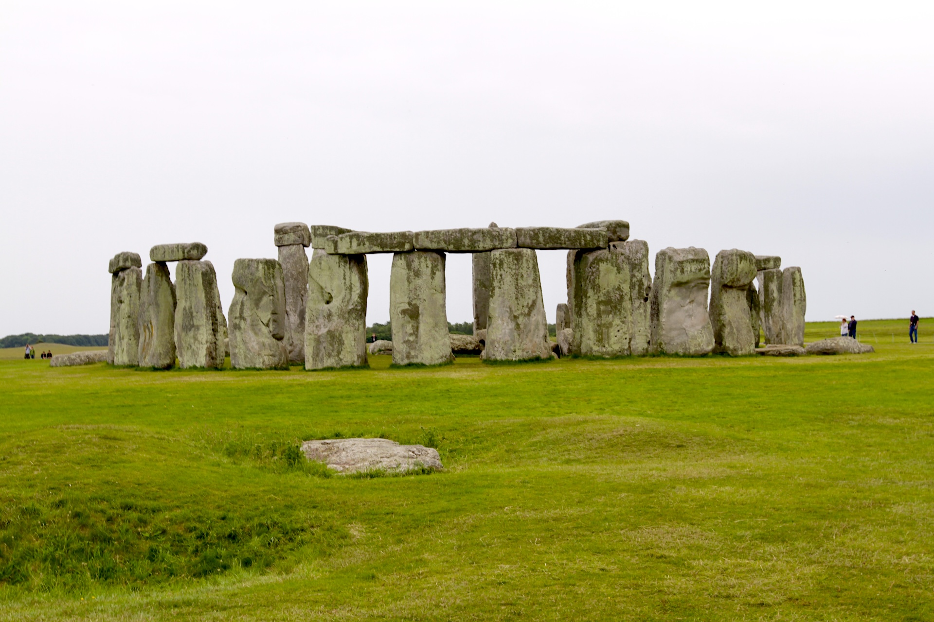 Stonehenge standing stones on a green field under an overcast sky