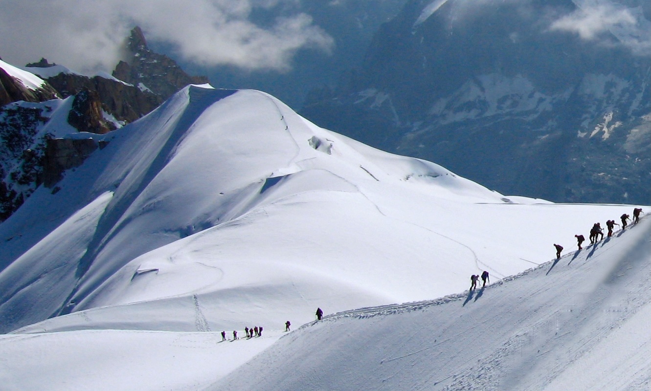 Mountaineers descending a snowy ridge in the Swiss Alps