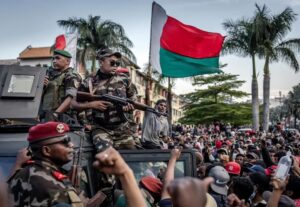 Madagascar Gen Z protesters wave national flags under army watch in October 2025.