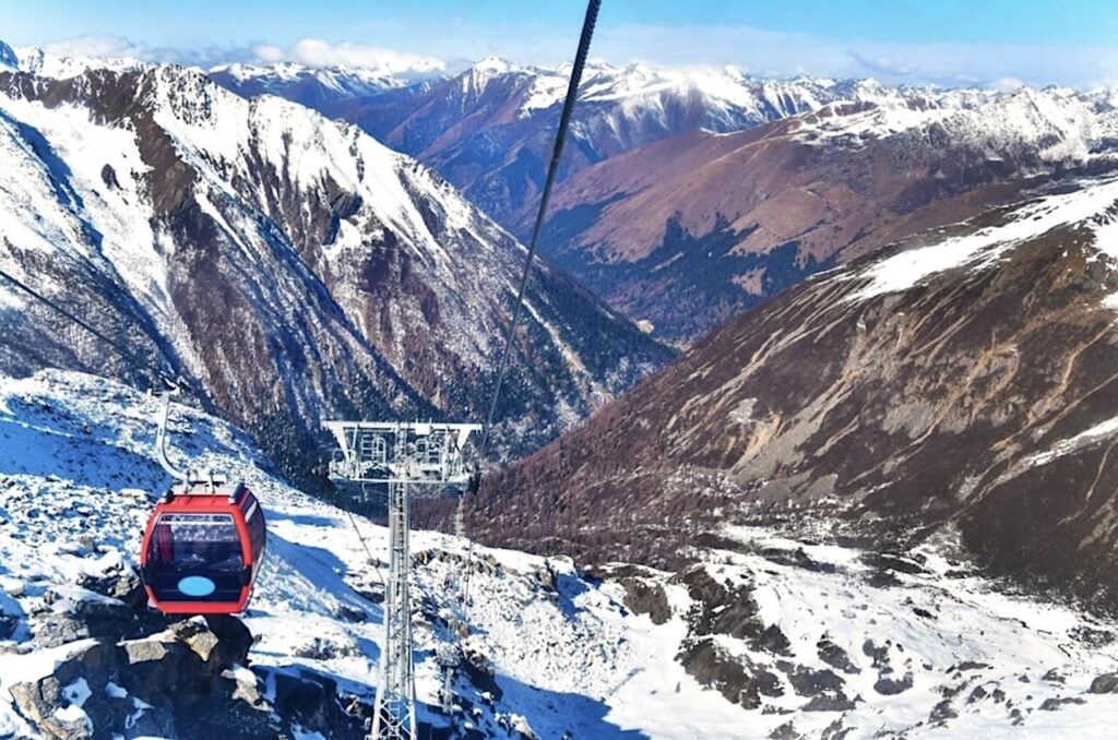 Dagu Glacier Gondola ascending above snow-covered mountains in Sichuan, China.