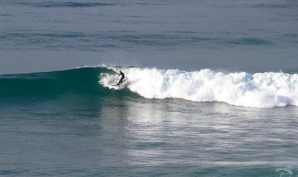 Surfer riding waves along the Great Ocean Road coast