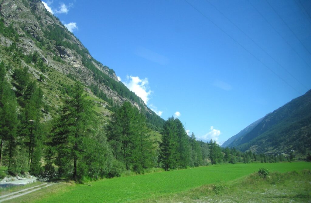 Lush green valley farmland nestled between mountains just before Zermatt