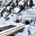 Elevated view of twin tunnel portals and bridge infrastructure surrounded by deep snow in the Himalayas - a part of the Zojila Tunnel project.