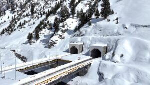 Elevated view of twin tunnel portals and bridge infrastructure surrounded by deep snow in the Himalayas - a part of the Zojila Tunnel project.